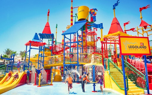 Families playing at LEGOLAND® Dubai Waterpark with colorful slides and water features.