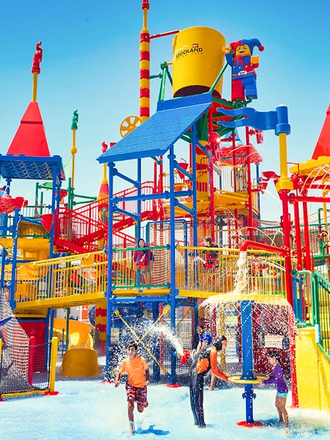 Families playing at LEGOLAND® Dubai Waterpark with colorful slides and water features.
