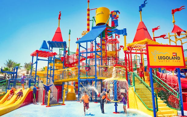 Families playing at LEGOLAND® Dubai Waterpark with colorful slides and water features.
