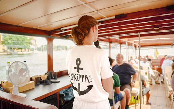Guide speaking to passengers on a classic wooden boat in the Stockholm Archipelago.