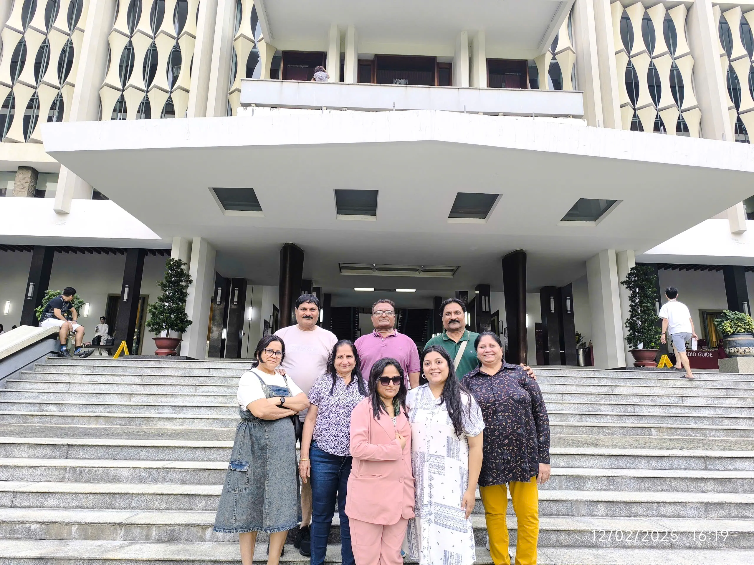 Group visiting historical site in Ho Chi Minh City, standing on steps of a significant building.