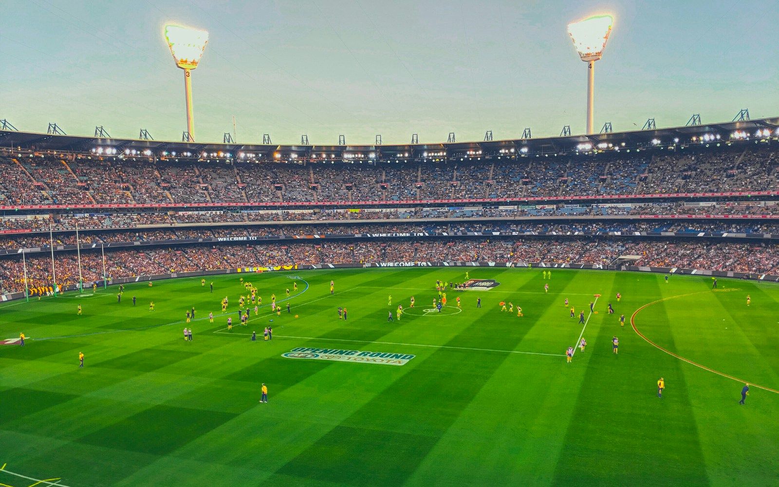 Australian Rules football match at Melbourne Cricket Ground with players on the field.