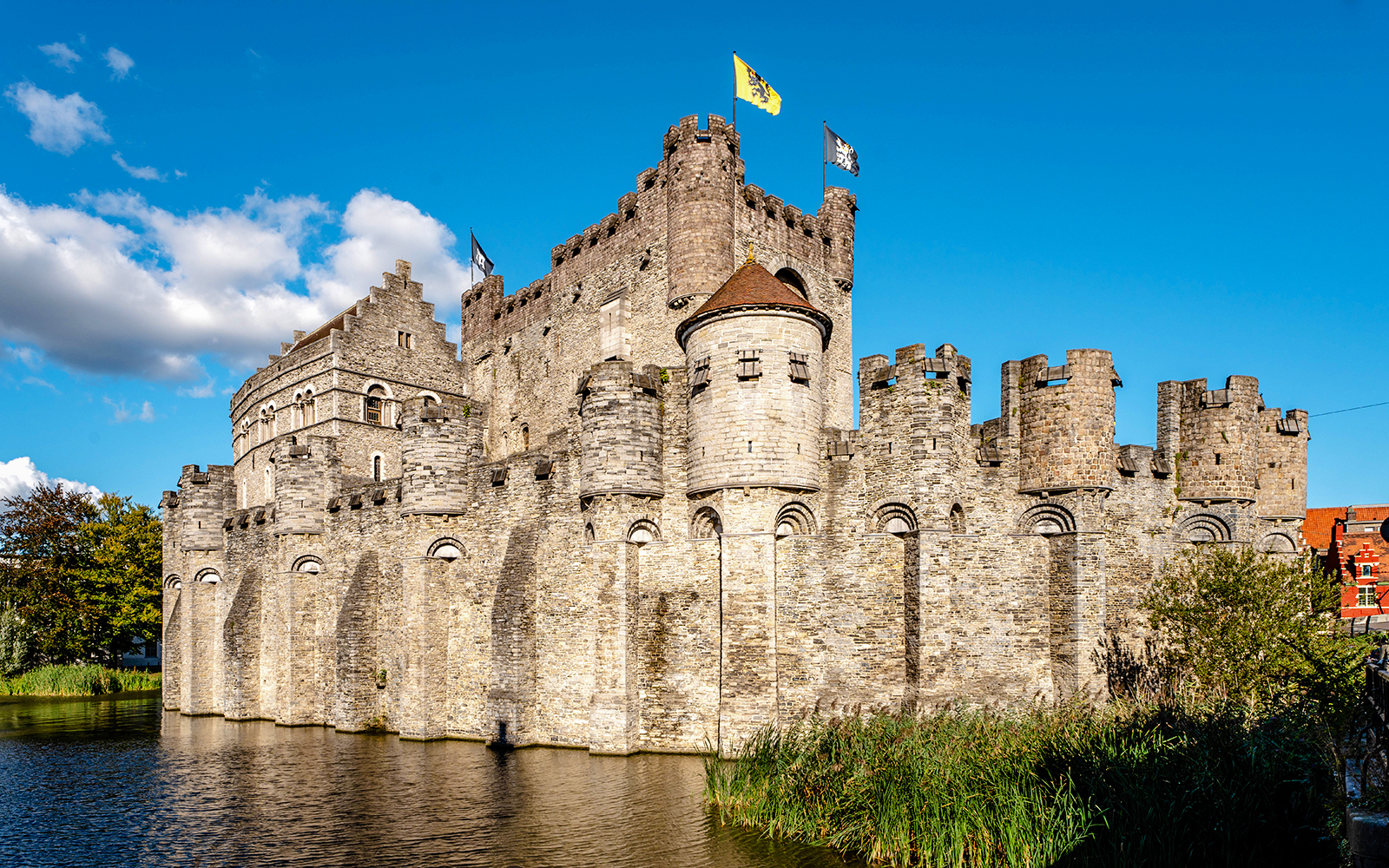 Gravensteen Castle with flags, surrounded by a moat in Ghent, Belgium.