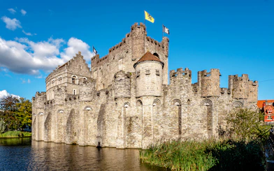 Gravensteen Castle with flags, surrounded by a moat in Ghent, Belgium.