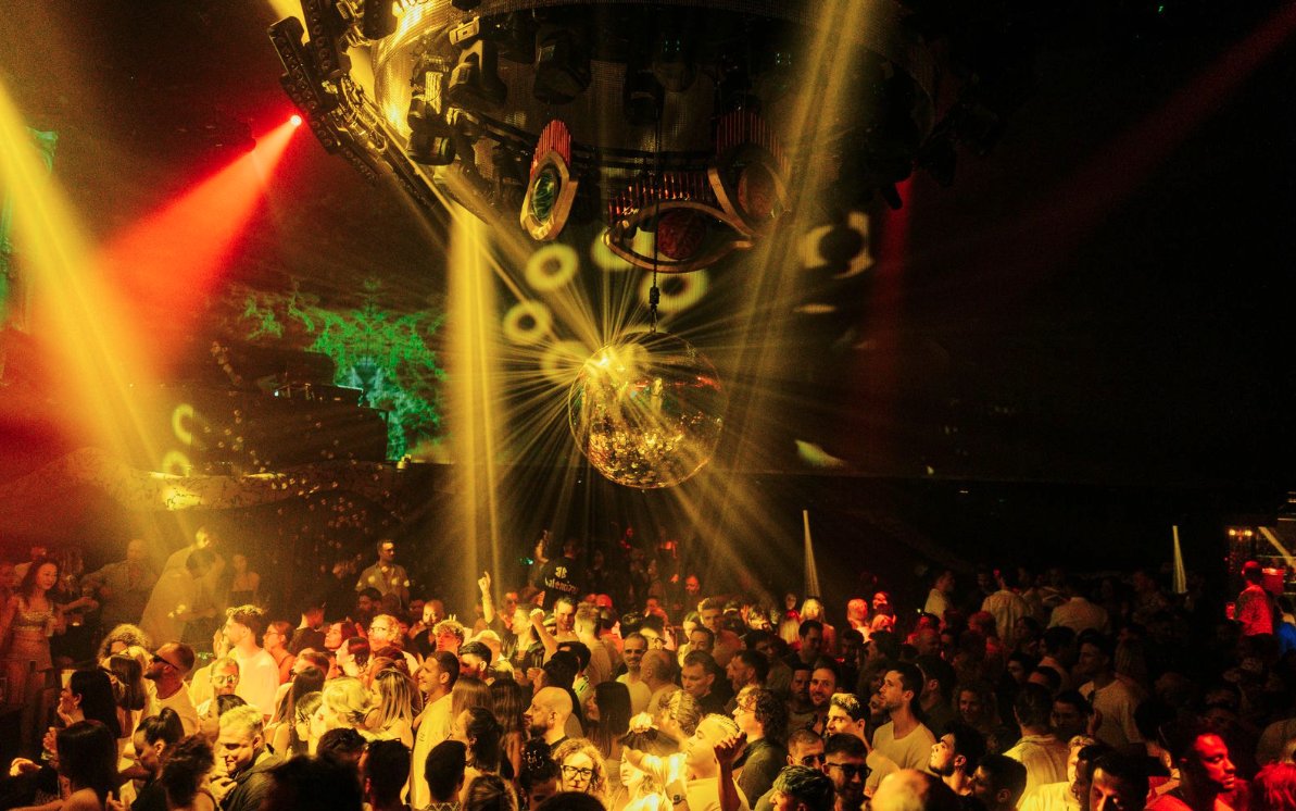 DJ performing at The Masquerade by Claptone, Ibiza nightclub with crowd and disco lights.