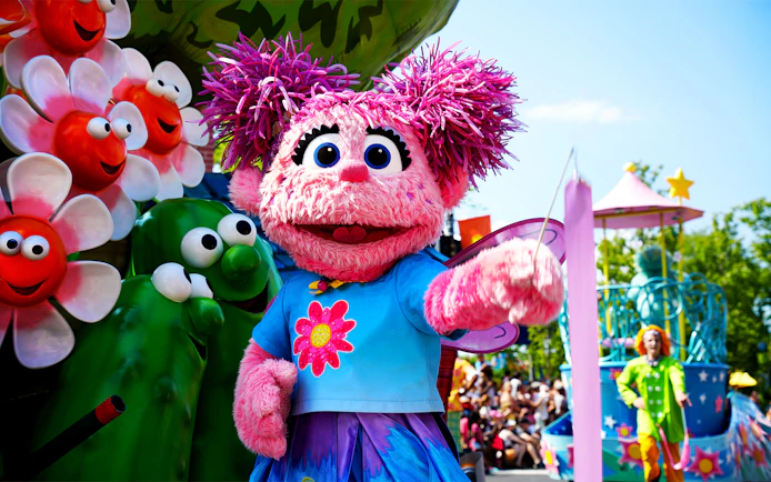 Sesame Place Philadelphia parade with pink character and colorful floats.