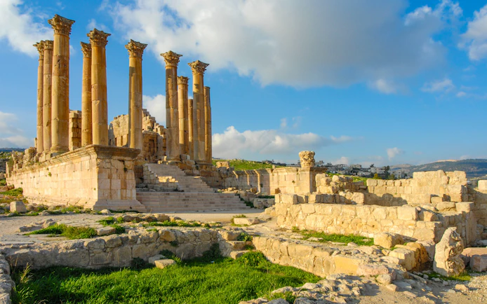 Ancient Roman columns and ruins in Jerash, Jordan under a blue sky.
