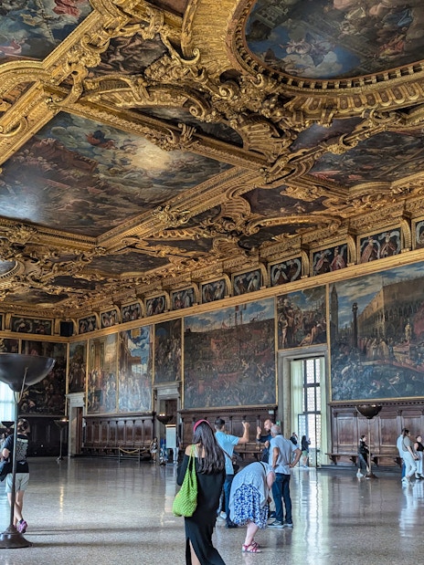 Visitors exploring the ornate interior of the Doge's Palace in Venice.