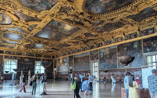 Visitors exploring the ornate interior of the Doge's Palace in Venice.