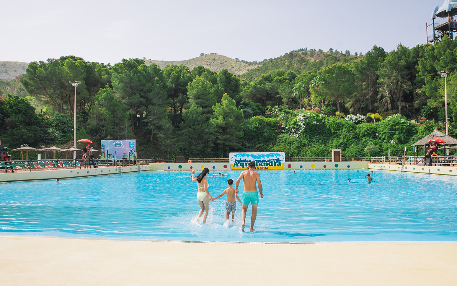 Family entering wave pool at Aqualandia Benidorm with lush greenery in the background.