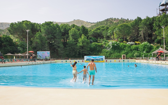 Family entering wave pool at Aqualandia Benidorm with lush greenery in the background.