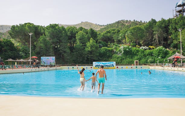 Family entering wave pool at Aqualandia Benidorm with lush greenery in the background.