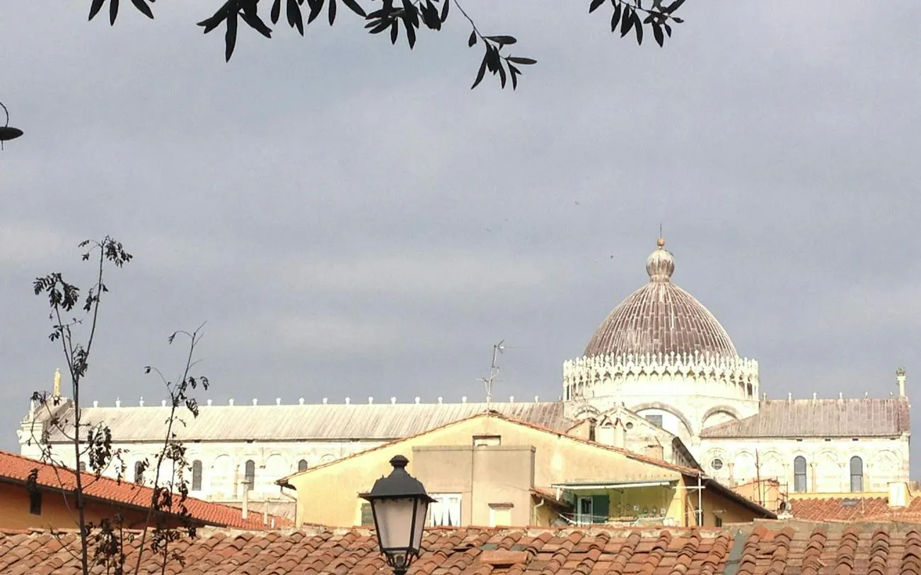 Pisa Cathedral dome viewed over rooftops, part of Pisa Romantic Walk exploration game.