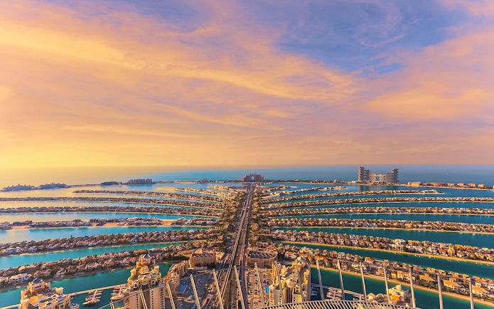 Aerial view of Palm Jumeirah in Dubai at sunset, showcasing the iconic palm-shaped islands.