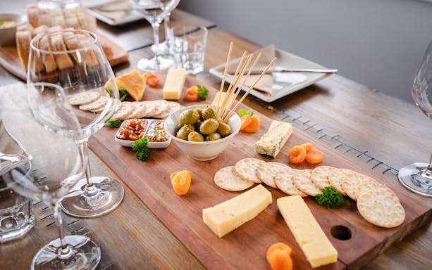 Cheese and olive platter with wine glasses on a Queenstown wine tour.