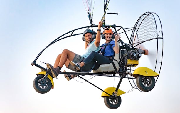 Two people enjoying a paramotor flight during an adventure tour.