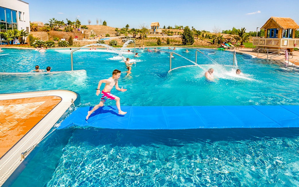 Children playing in a pool at Tropical Islands Resort, featuring water slides and splash areas.