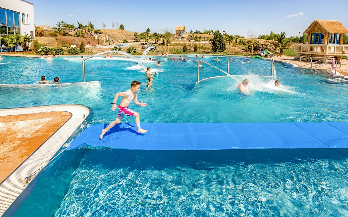 Children playing in a pool at Tropical Islands Resort, featuring water slides and splash areas.