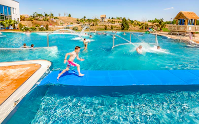 Children playing in a pool at Tropical Islands Resort, featuring water slides and splash areas.
