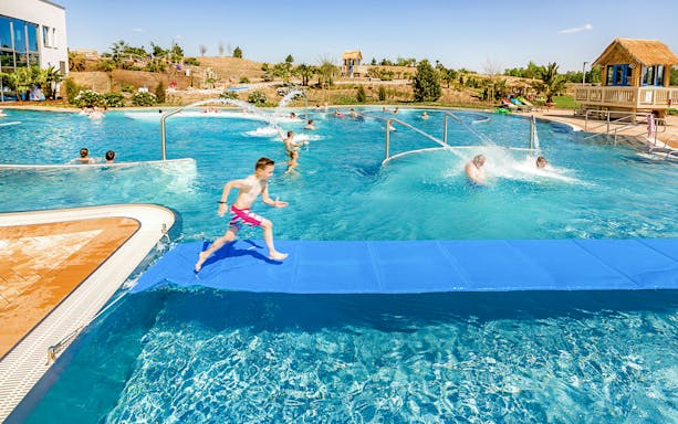 Children playing in a pool at Tropical Islands Resort, featuring water slides and splash areas.