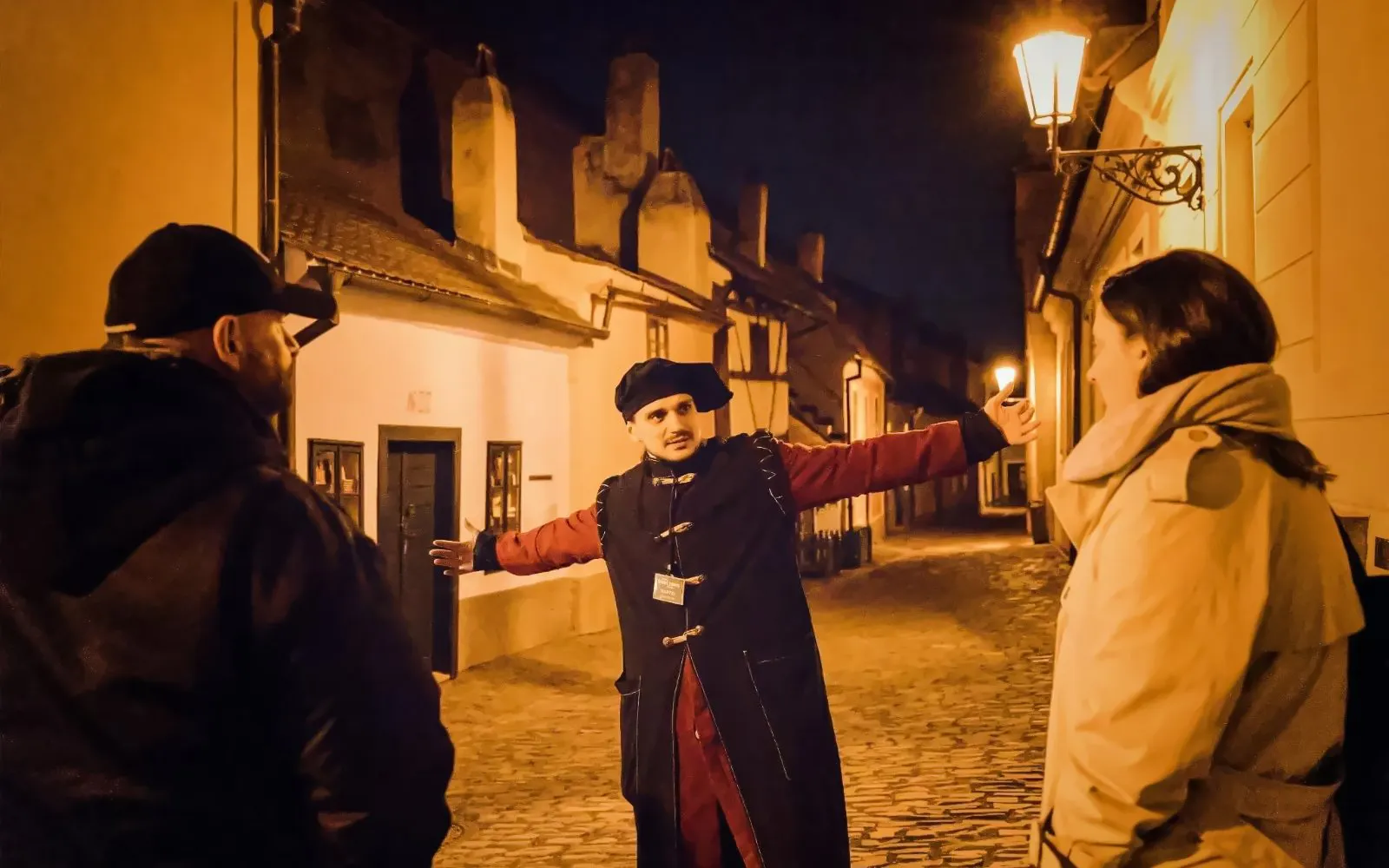 Tour guide in historical attire leading a night tour at Prague Castle.