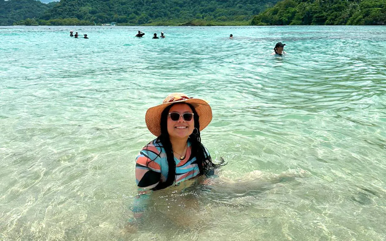 Person enjoying the clear waters at Isla Mamey, Panama, with lush greenery in the background.