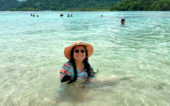 Person enjoying the clear waters at Isla Mamey, Panama, with lush greenery in the background.