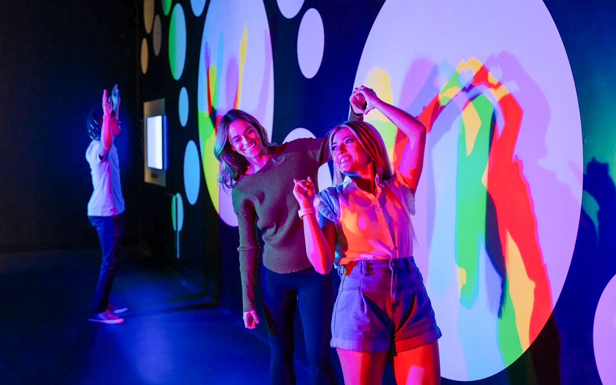 Visitors interacting with colorful light displays at Paradox Museum Paris.
