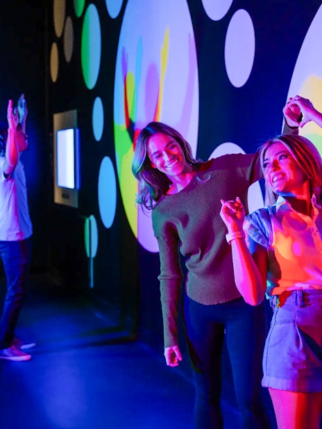 Visitors interacting with colorful light displays at Paradox Museum Paris.