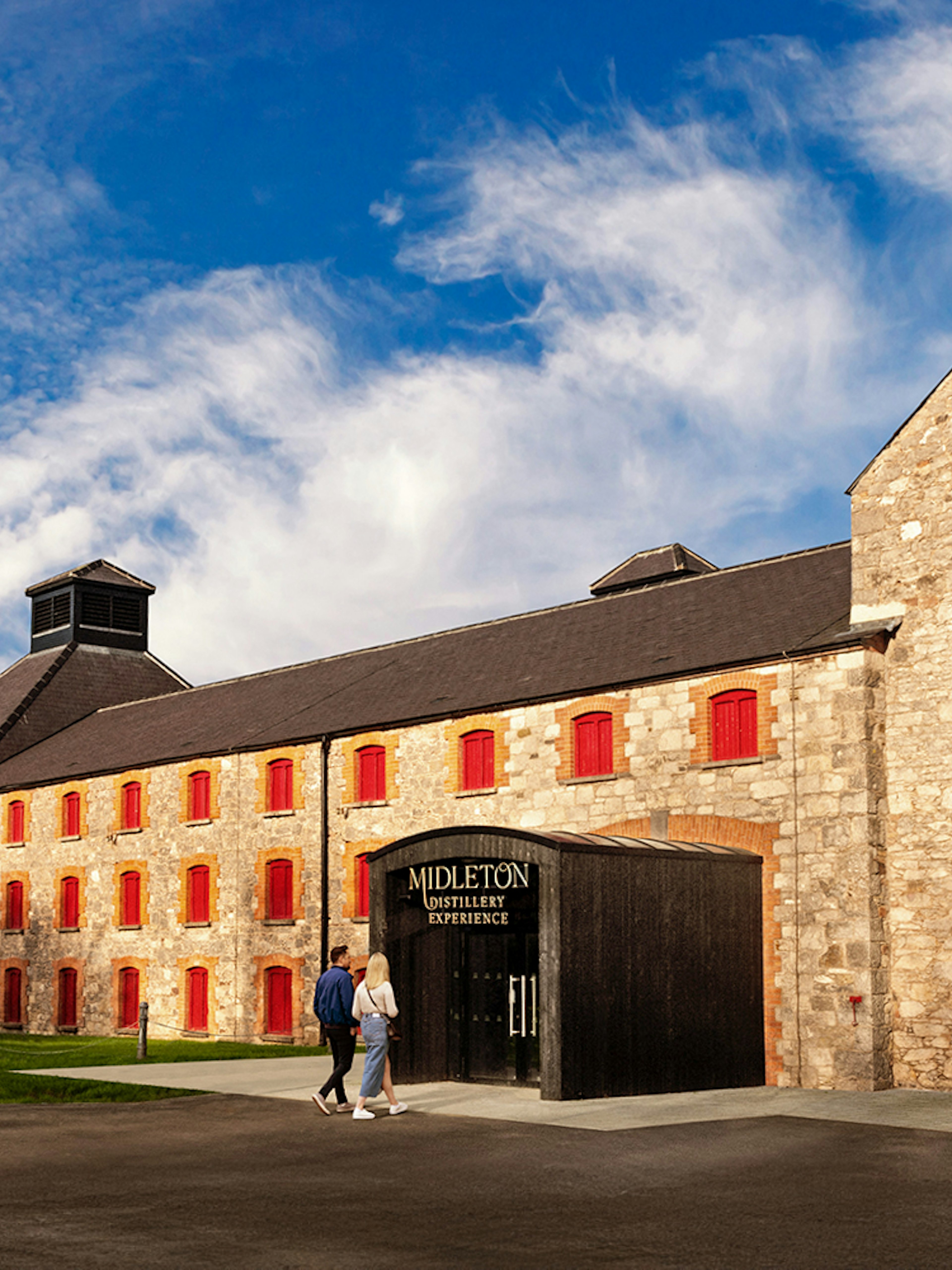 Entrance to Midleton Distillery Experience with copper pot still and stone building.