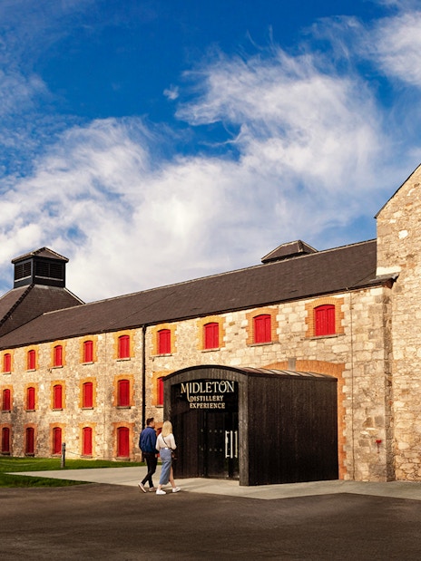 Entrance to Midleton Distillery Experience with copper pot still and stone building.