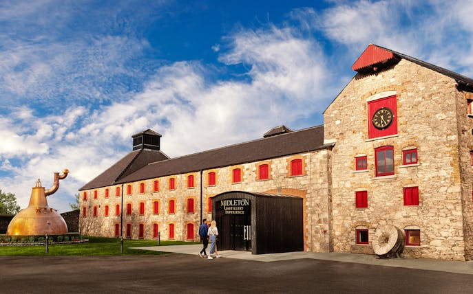 Entrance to Midleton Distillery Experience with copper pot still and stone building.