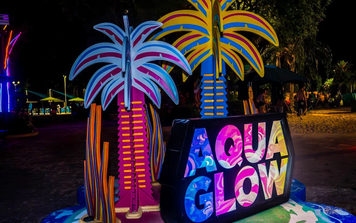 AquaGlow neon sign with colorful palm trees at Aquatica San Antonio.