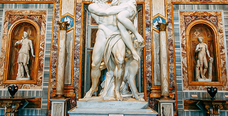 Borghese Gallery interior with classical sculptures and Renaissance paintings in Rome, Italy.