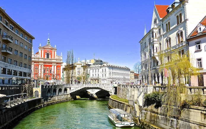 Ljubljanica River with a boat near historic buildings in Ljubljana city center.