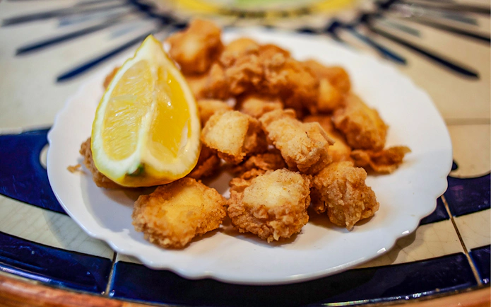 Fried seafood with lemon on a plate during La Barceloneta food tour.