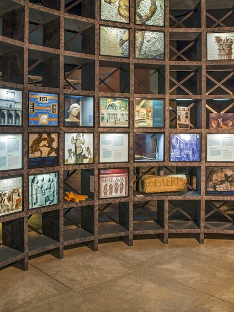 Exhibit at Pont du Gard museum with historical displays and visitor interacting with a screen.