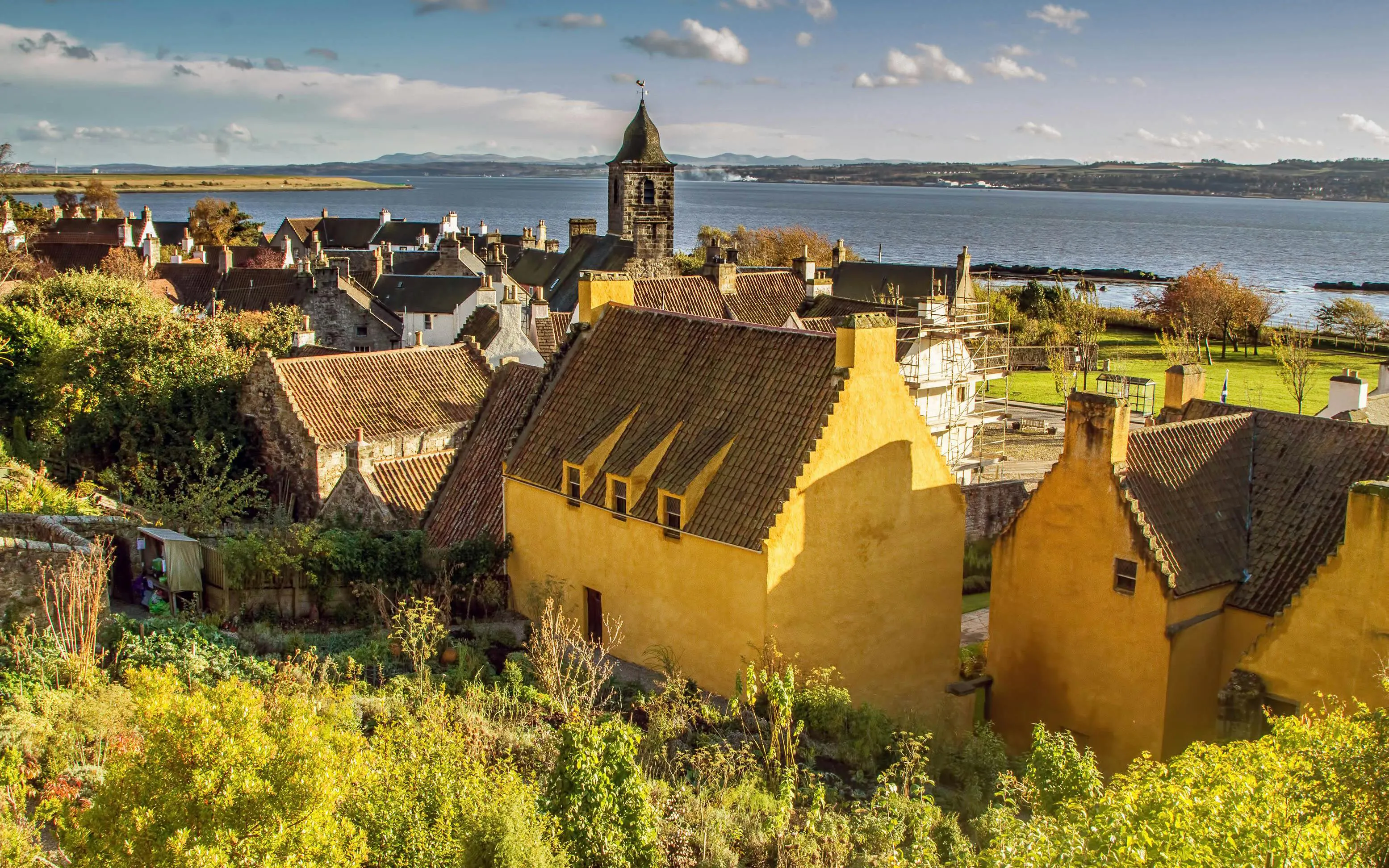 Culross village with historic yellow houses and church tower by the Firth of Forth, Scotland.
