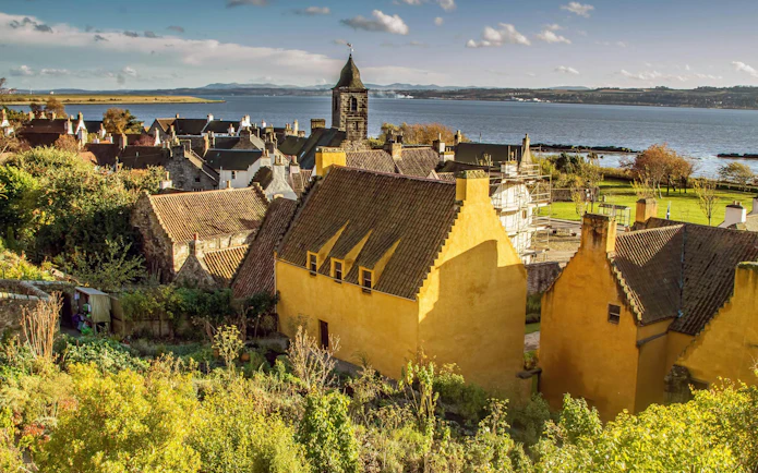 Culross village with historic yellow houses and church tower by the Firth of Forth, Scotland.