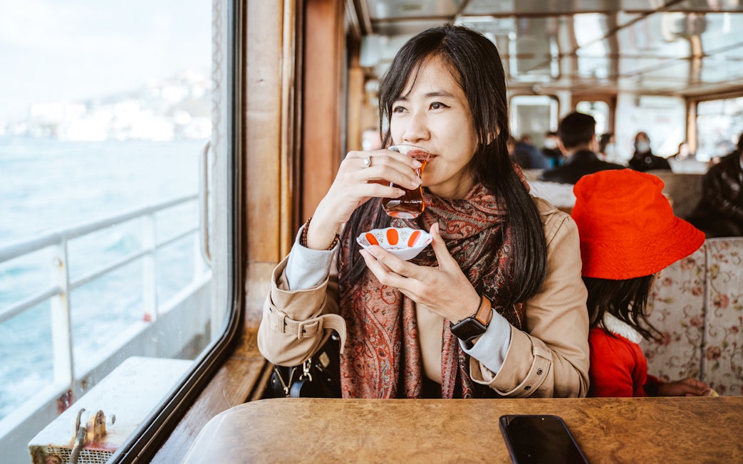 Woman enjoying Turkish tea on a ferry boat.