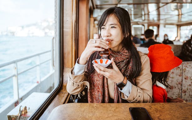 Woman enjoying Turkish tea on a ferry boat.