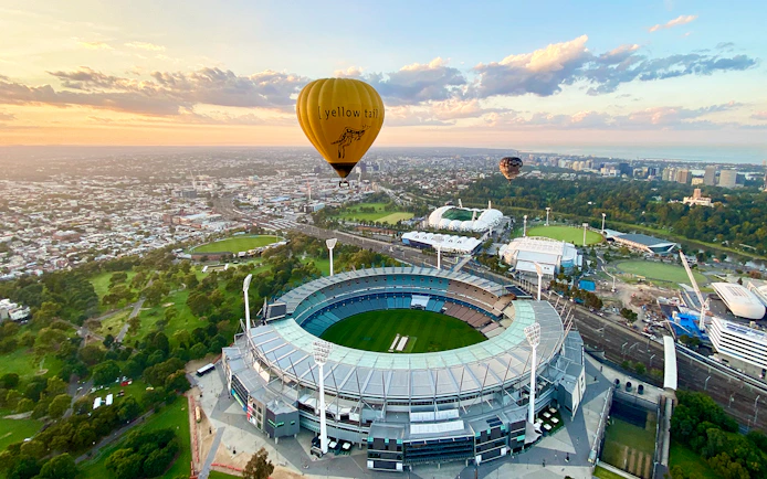 Hot air balloon over Melbourne Cricket Ground at sunrise.