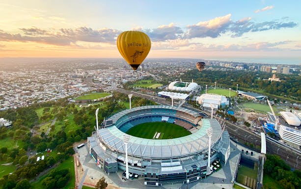 Hot air balloon over Melbourne Cricket Ground at sunrise.