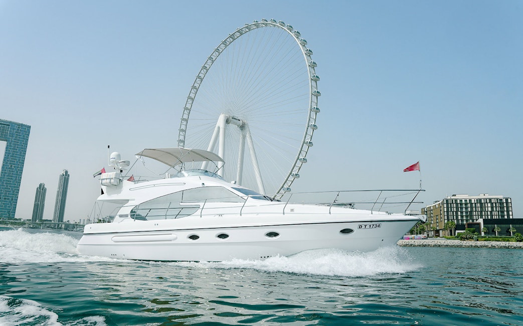 Luxury yacht cruising with Ain Dubai wheel in the background.
