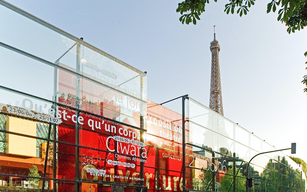 Quai Branly Museum glass facade with Eiffel Tower in background, Paris.