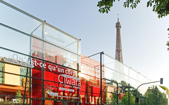 Quai Branly Museum glass facade with Eiffel Tower in background, Paris.