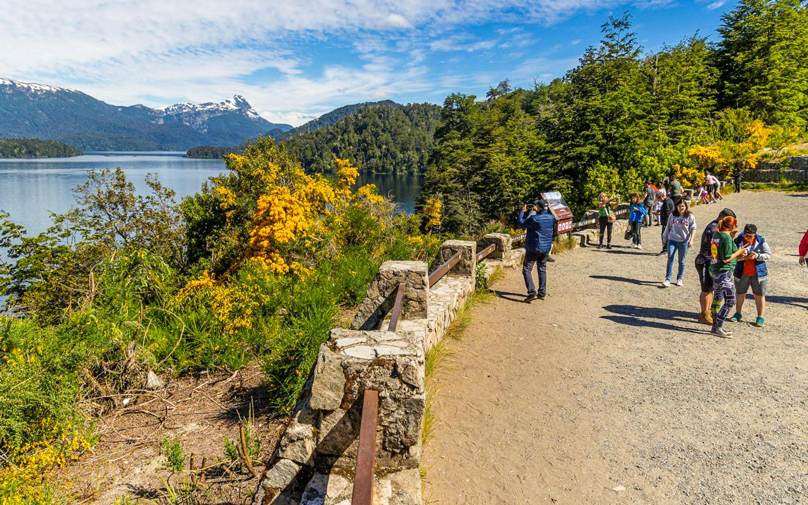 Scenic overlook with tourists enjoying panoramic views of lakes and forests in Patagonia.