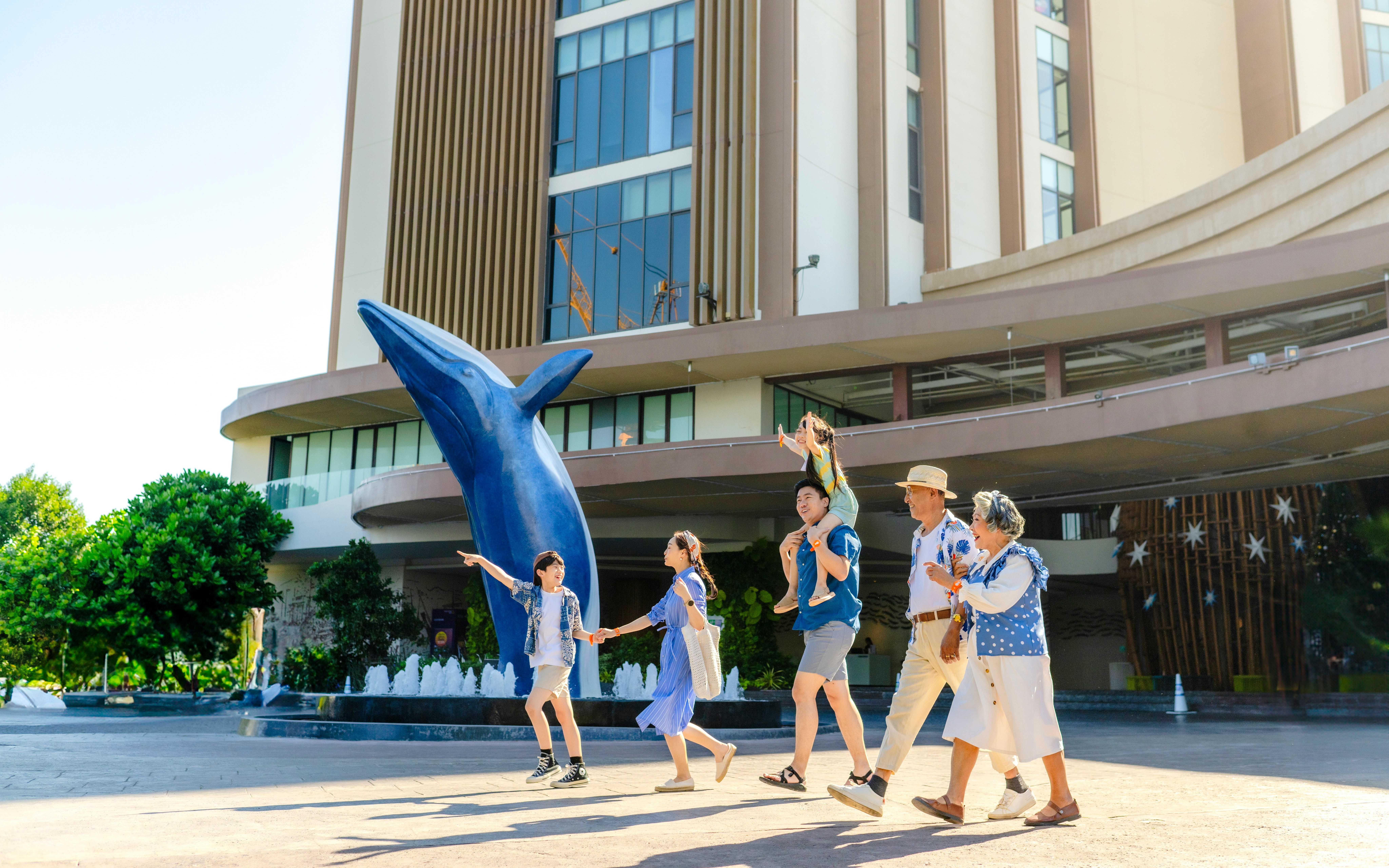 Family walking past dolphin statue at Vana Nava Water Jungle entrance.