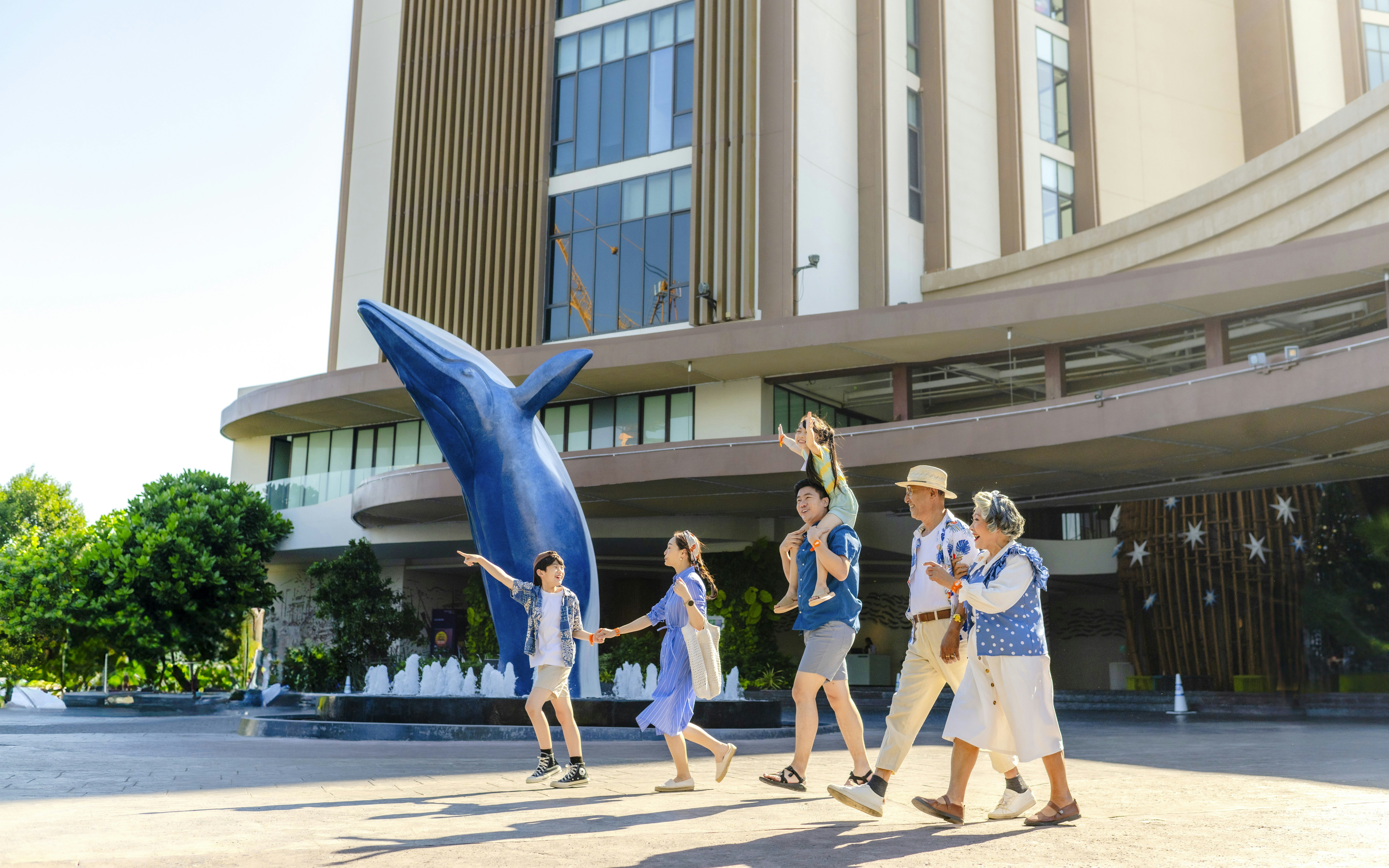 Family walking past dolphin statue at Vana Nava Water Jungle entrance.