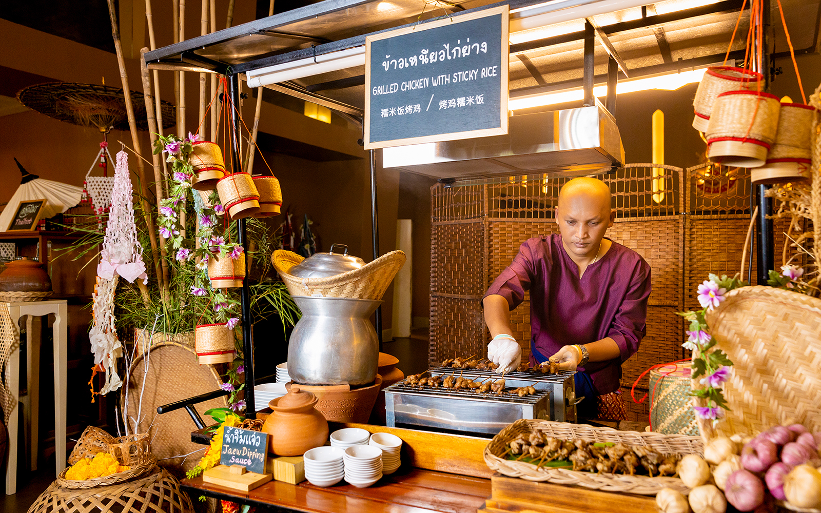 Vendor grilling chicken at buffet in Siam Niramit, Bangkok.